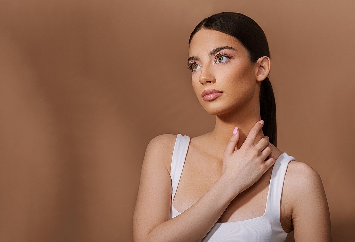 Model with elegant hairstyle against brown background.