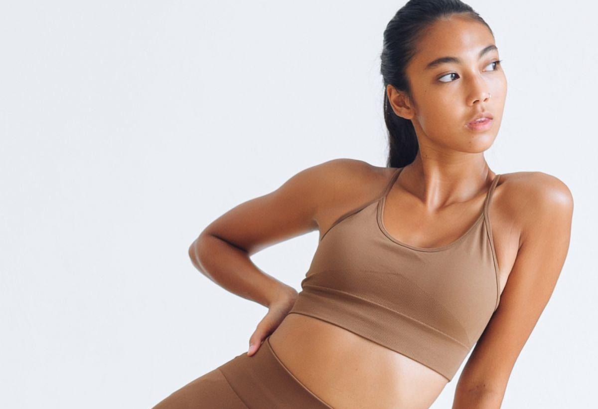 Fitness model in brown athletic wear posing gracefully.