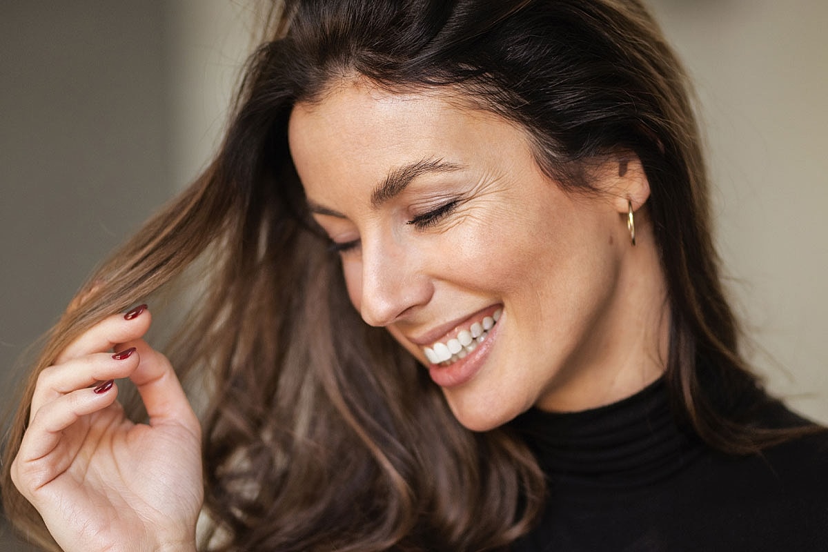 Smiling woman touching her hair softly.