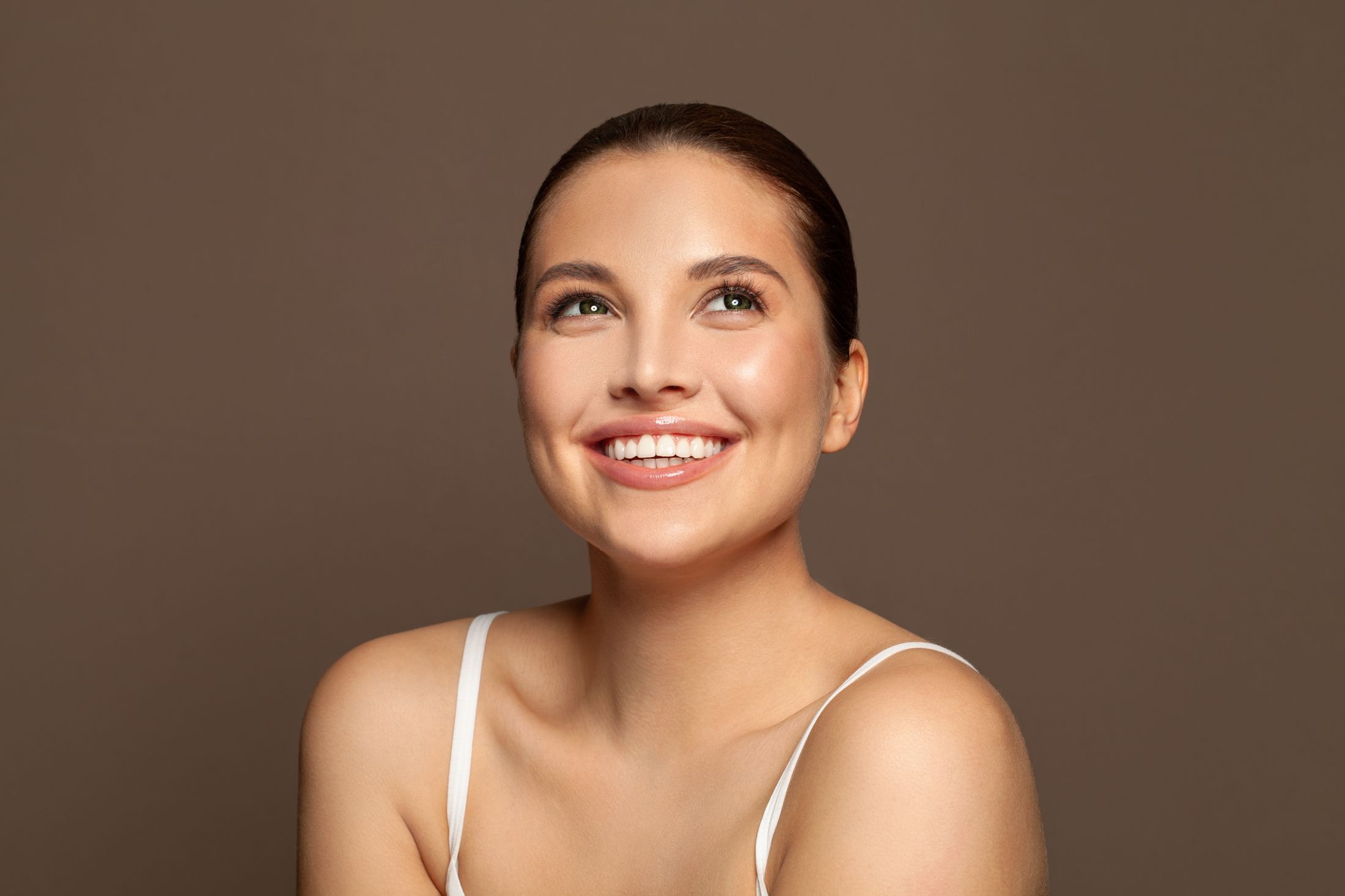 Smiling woman with glowing skin and natural makeup.