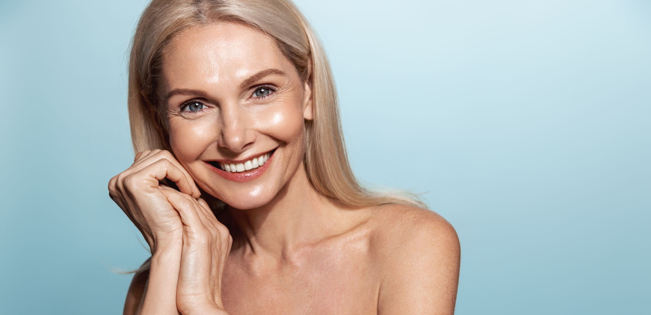 Smiling woman with long blonde hair against blue background.