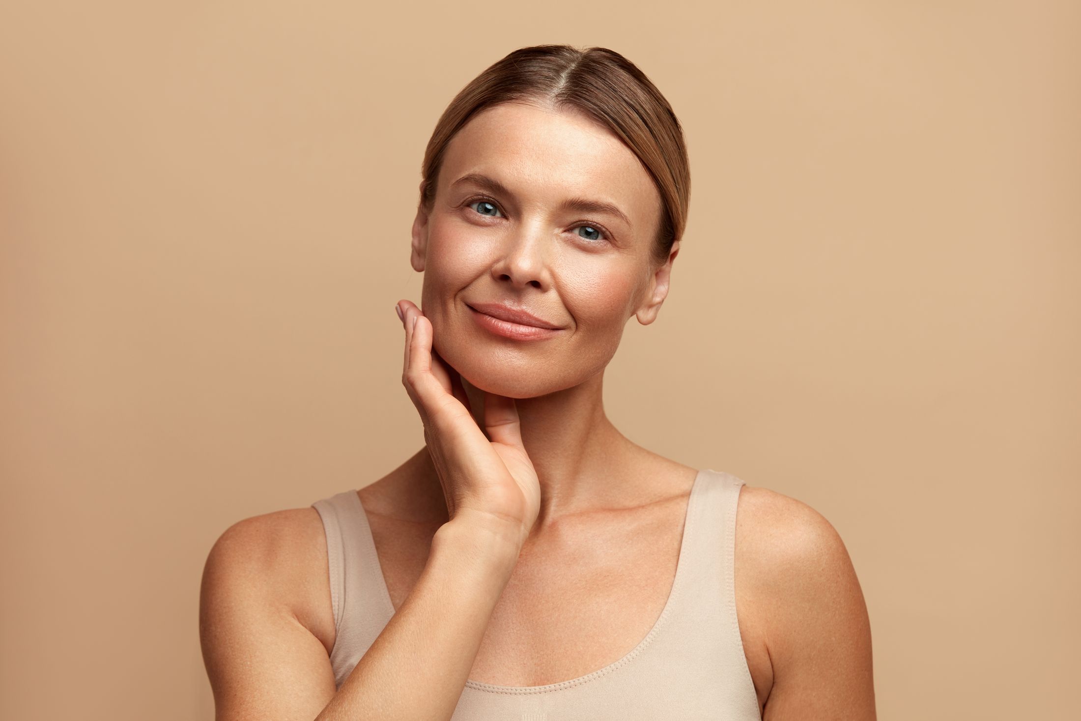 Woman gently touching her face, smiling confidently.